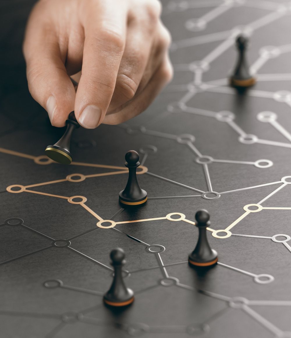 A hand moves a chess pawn on a dark surface with interconnected lines and nodes, surrounded by other pawns, symbolizing strategy and planning.